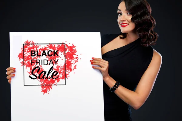 Black Friday försäljning koncept med vacker flicka med lockigt hår. Porträtt av ung, vacker och frisk kvinna med en tom vit banner. — Stockfoto