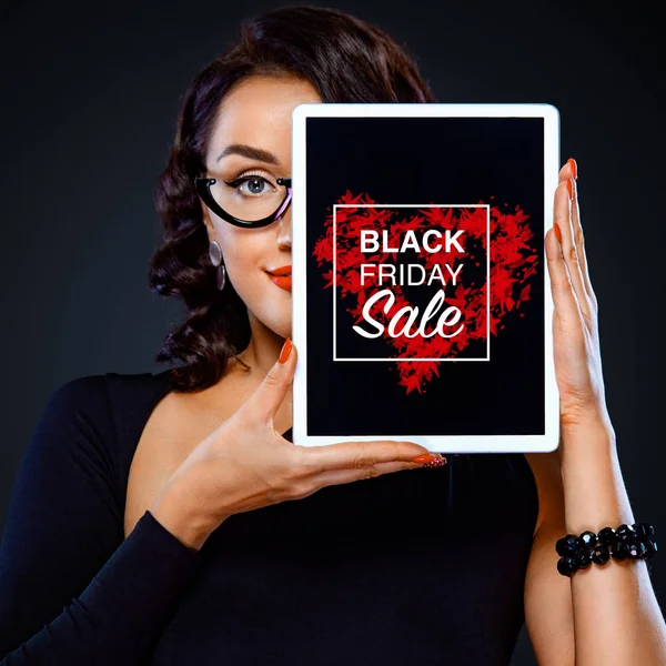 Viernes Negro y Cyber lunes concepto de venta para tienda. Retrato de primer plano de mujer con tableta aislada sobre fondo oscuro. Exitosa mujer de negocios en gafas . — Foto de Stock