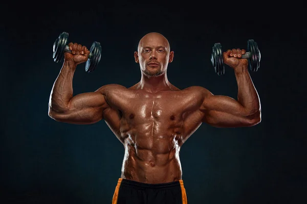 Bodybuilder uomo forte e in forma. Un tipo muscoloso e sportivo con i manubri. Sport e motivazione al fitness. Attività ricreative sportive individuali . — Foto Stock