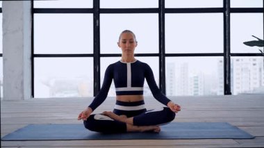 Genç ve güzel bir kadının portresi. Mudra ve namaste yoga pozu. İçeride meditasyon için. Bireysel sporlar. Spor eğlencesi..