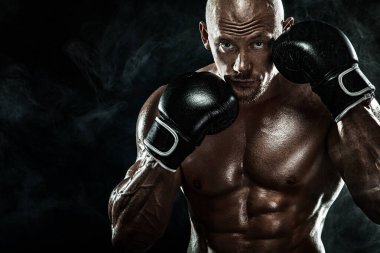Sporcu, erkek boksör siyah arka planda eldivenlerle dövüşüyor. Fitness ve boks konsepti. Bireysel spor eğlencesi.