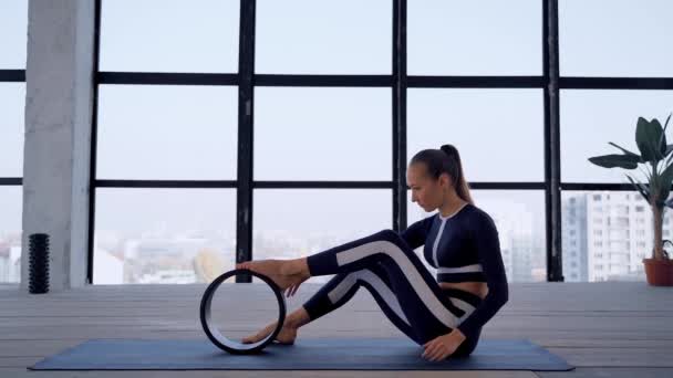 Yoga binnen. Sport recreatie. Mooie jonge vrouw in asana met yoga ring voor beginners. Individuele sporten. Kamer met groot panoramisch raam. — Stockvideo
