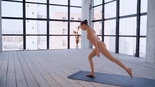 Yoga inomhus. Sportrekreation. Vacker ung kvinna i yoga asana för nybörjare. Enskilda sporter. Rum med stort panoramafönster. — Stockvideo