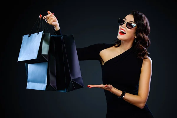 검은 금요일 쇼핑 컨셉이야. 쇼핑 할 때 선글라스 가방을 들고 어두운 배경에 고립된 소녀. 판매용 사본을 찾는 여자. — 스톡 사진