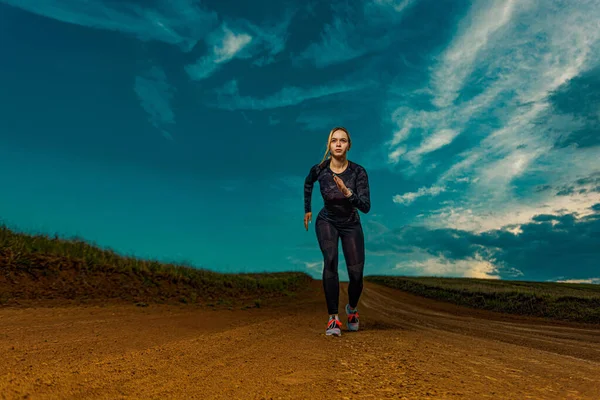 户外运动。身材苗条的年轻女子,适合在空中跑步的运动员.健康的生活方式和运动的概念。穿黑色衣服的女人. — 图库照片
