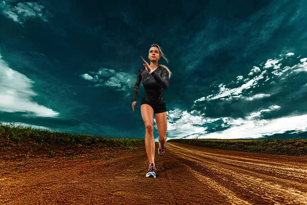 Fitness afuera. Mujer joven deportiva y atleta en forma corredor corriendo sobre el fondo del cielo. El concepto de un estilo de vida saludable y el deporte. Mujer en ropa deportiva negra . — Foto de Stock