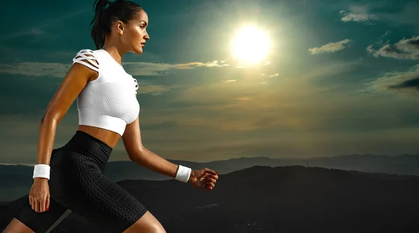 身材苗条的年轻女子和健康的运动员跑步者在高山的天空背景下奔跑.健康的生活方式和运动的概念。身穿黑白运动服的妇女. — 图库照片