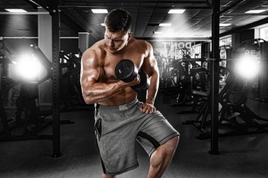 Zalim güçlü kaslı vücut geliştirici atletik adam spor salonunda halterle kaslarını şişiriyor. Vücut geliştirme konsepti. Spor beslenme reklamları için alanı kopyala.