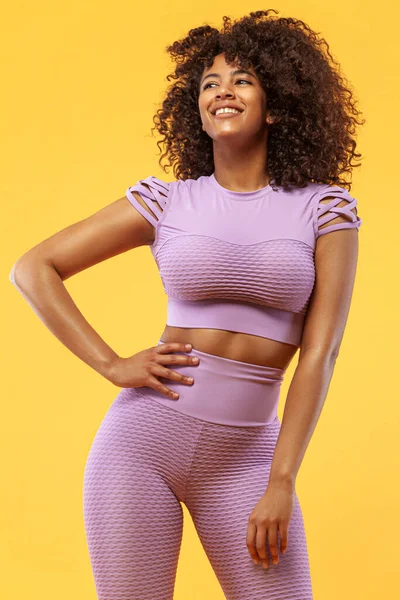 Concepto de estilo de vida. Retrato de hermosa mujer afroamericana feliz y bailando con el pelo rizado. Fondo amarillo del estudio. Copiar espacio . —  Fotos de Stock