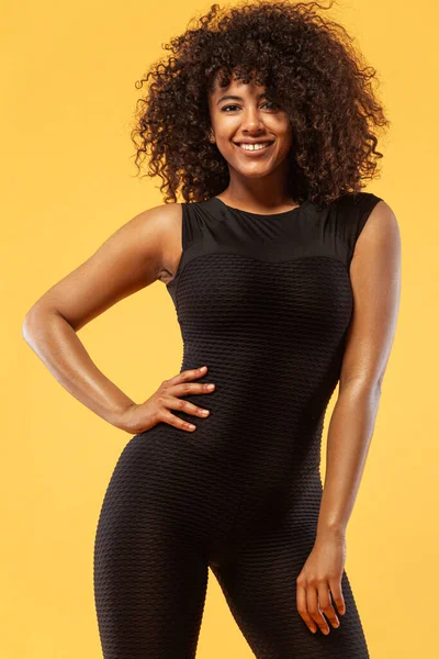 Lifestyle concept. Portret van een prachtige vrolijke en dansende Afro-Amerikaanse vrouw met krullend haar. Gele studio achtergrond. Kopieer ruimte.. — Stockfoto