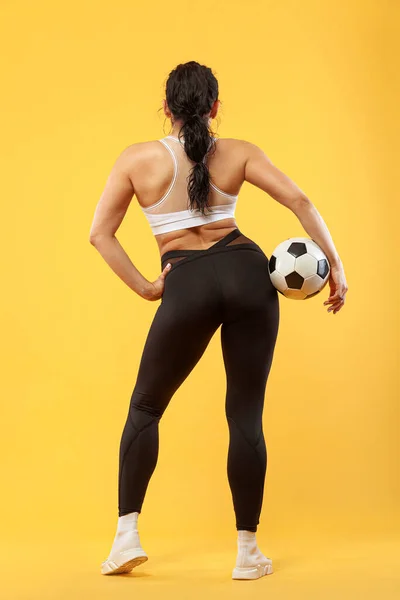 Size plus woman sporty fit woman in sportswear with soccer ball, athlete makes fitness exercising on yellow background. Motivation for fat people. — Stock Photo, Image