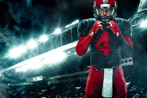 Americký fotbalista, sportovec v červené helmě na pozadí stadionu. Sportovní a motivační tapety. — Stock fotografie