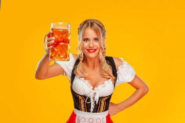 Genç seksi Ekim Festivali kız garsonu, geleneksel bir Bavyera ya da Alman dirndl giyiyor. Sarı arka planda büyük bira bardakları ve içki servisi yapan bir kadın..