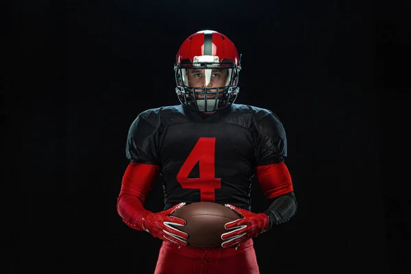 Αμερικανός ποδοσφαιριστής, αθλητής με κόκκινο κράνος σε μαύρο φόντο. Αθλητισμός και κίνητρο ταπετσαρία. — Φωτογραφία Αρχείου