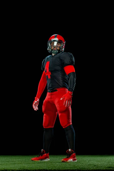 Joueur de football américain, sportif sportif en casque rouge sur fond noir. Sport et papier peint de motivation. — Photo