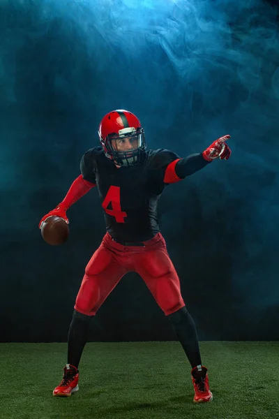 Jogador de futebol americano, atleta desportista em capacete vermelho no fundo escuro com fumaça. Esporte e motivação papel de parede. — Fotografia de Stock