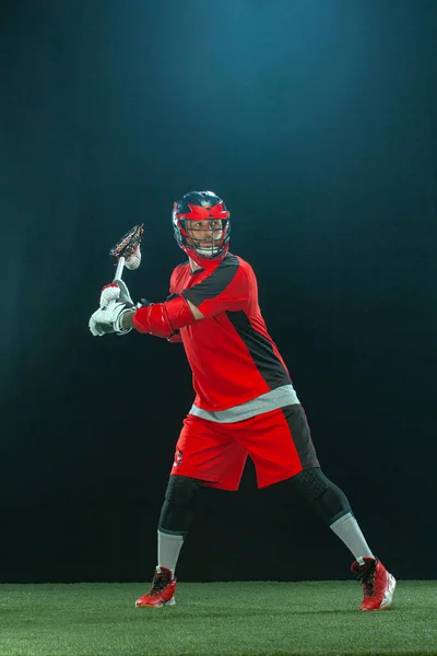 Lakros hráč, sportovec v červené přilbě na tmavém pozadí. Sportovní a motivační tapety. — Stock fotografie