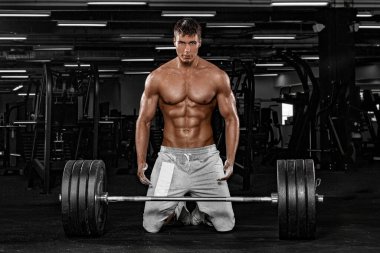 Spor salonundaki kaslı erkek sporcu antrenman yapıyor. Spor eğitmeni halterle antrenman yapıyor..
