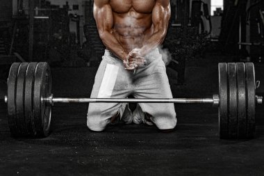 Spor salonundaki kaslı erkek sporcu antrenman yapıyor. Spor eğitmeni halterle antrenman yapıyor..
