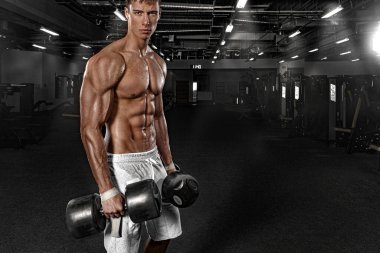 Spor salonundaki kaslı erkek sporcu antrenman yapıyor. Spor eğitmeni halterlerle antrenman yapıyor..