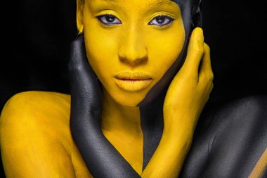 Yüz sanatı. Siyah ve sarı vücut boyalı bir kadın. Renkli vücut boyalı Afrikalı genç bir kız. Sarı makyajlı harika bir model. Yakından bak..