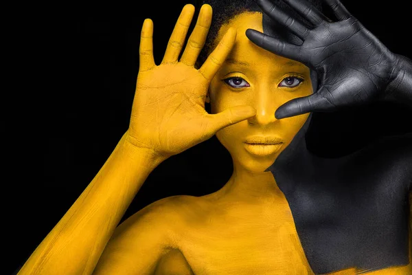 Twarzą w twarz. Kobieta z czarno-żółtą farbą do ciała. Młoda afrykańska dziewczyna z kolorowym farbą do ciała. Niesamowity model z żółtym makijażem. Zbliżenie twarzy. — Zdjęcie stockowe