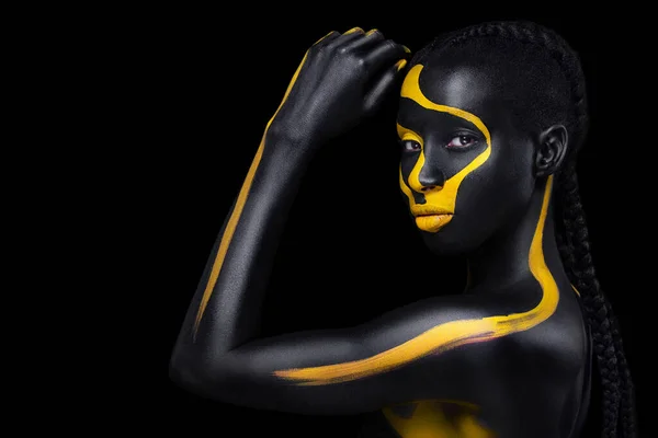 Viso artistico. Donna con carrozzeria nera e gialla. Giovane ragazza africana con carrozzeria colorata. Un modello incredibile con trucco giallo. Primo piano del viso. — Foto Stock