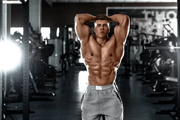 Homem atleta fisiculturista bombeando músculos no ginásio. Brutal forte cara muscular no treino de fitness. Conceito de halterofilismo. — Fotografia de Stock