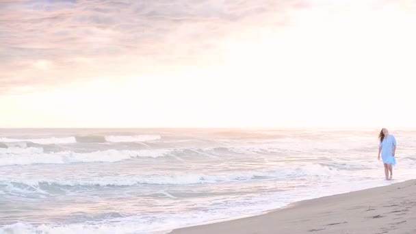 Günbatımı sahil boyunca yürüyen kadın — Stok video