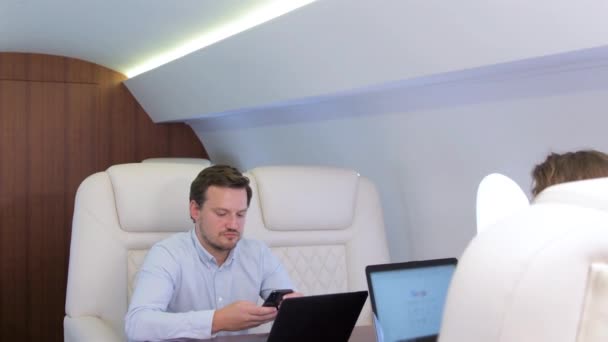 Two businessmen comfortably work on private plane — Stock Video