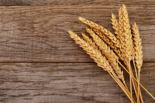 Tahta arka planda izole edilmiş buğday kulakları.