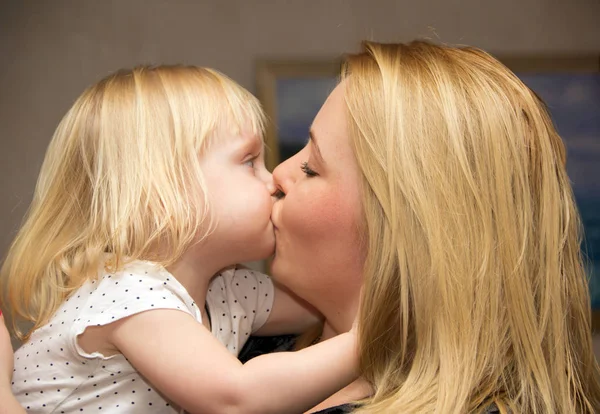 Blonde mom kissing her child