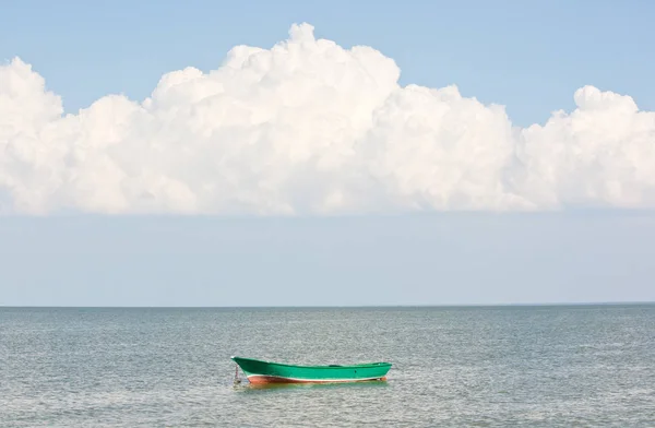 Beautiful white cloud over the sea. Green wooden boat on the sea