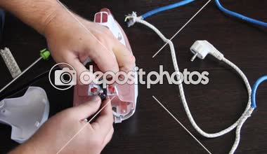 Bir adam bir elektrik demir onarır. Adamın elleri yakın çekim