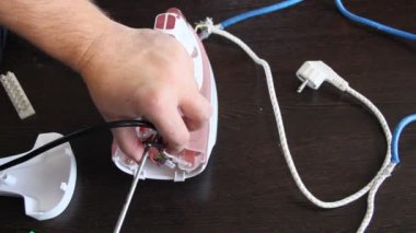 Bir adam bir elektrik demir onarır. Adamın elleri yakın çekim