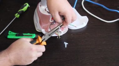 Bir adam bir elektrik demir onarır. Adamın elleri yakın çekim