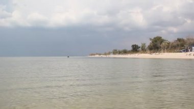 Sessiz deniz üzerinde fırtına bulutları. Turistler tükürmek sandy sakin ol.