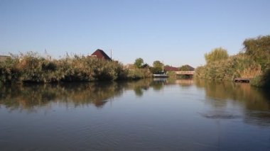 Sabah güneş tarafından aydınlatılmış kanal. Sazlık ile büyümüş kanal kıyısında.