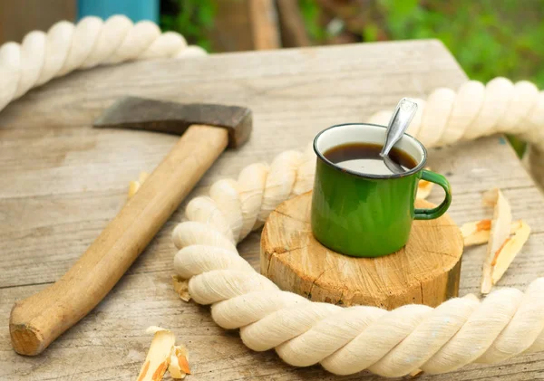 An axe and a mug on a wooden table. — Stock Photo, Image