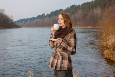 Açık havada fincanı olan romantik bir kız. Baharda manzarada çay içen hippi kız.