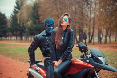 Spor motosikletli güzel bir hippi kızın portresi. Kafatası maskeli bir adamla.