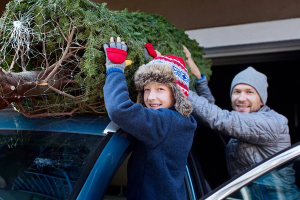 happy family christmas tree shopping, taking the tree off car roof, enjoying magical time together