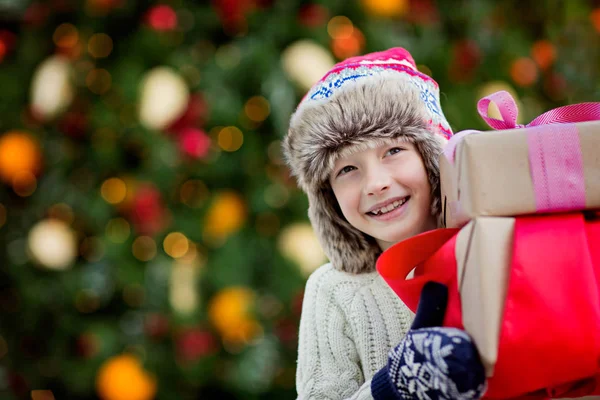 Bonito Sorrindo Menino Segurando Presentes Natal Com Árvore Decorada Fundo — Fotografia de Stock