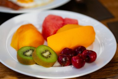 tabak dolusu taze dilimlenmiş egzotik meyve: kivi, tatlı kiraz, mango, papaya ve karpuz, lezzetli ve sağlıklı snack