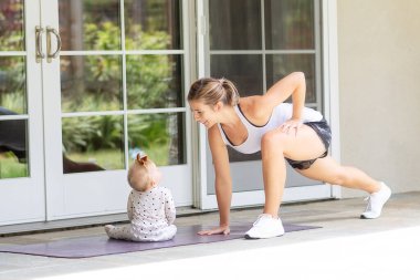 Genç anne, sağlıklı aile aktivitesi konseptiyle birlikte evde spor yapıyor.