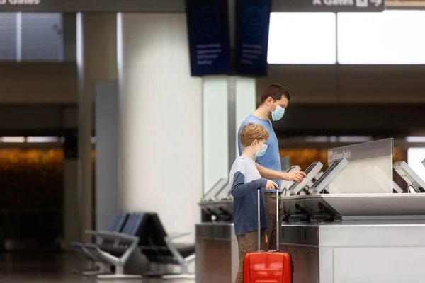 父と息子の2人家族空港の荷物を抱えた仮面の前でコロナウイルスのパンデミックの概念の間に旅行する — ストック写真