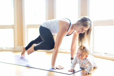 Yoga yapan genç bir anne evde bebeğiyle birlikte evde yemek yiyor. Sağlıklı aile aktiviteleri konsepti.