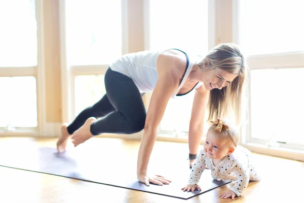 家でヨガのフィットネスをしている忙しい若い母親と赤ちゃんの家でのご注文の際健康的な家族活動のコンセプト ストック画像