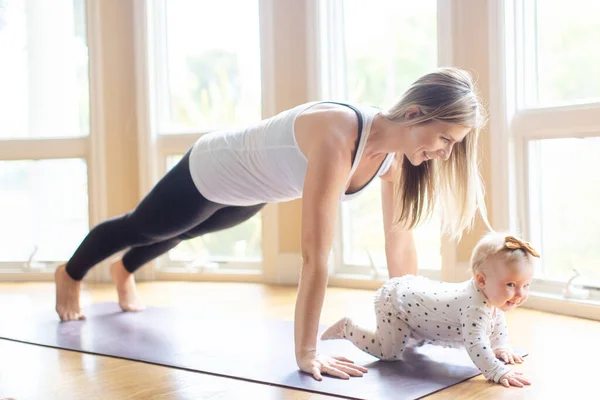 Zajęta Młoda Matka Robi Fitness Domu Wraz Dzieckiem Podczas Pobytu — Zdjęcie stockowe