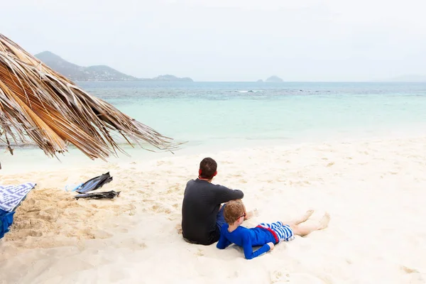 父親と息子の2人の家族のバックビューは ゆっくりと砂の上に横たわって Vincentと手榴弾 ビーチバケーションのコンセプトでモピオンの無人島で夏休みを楽しんでいます ストック写真